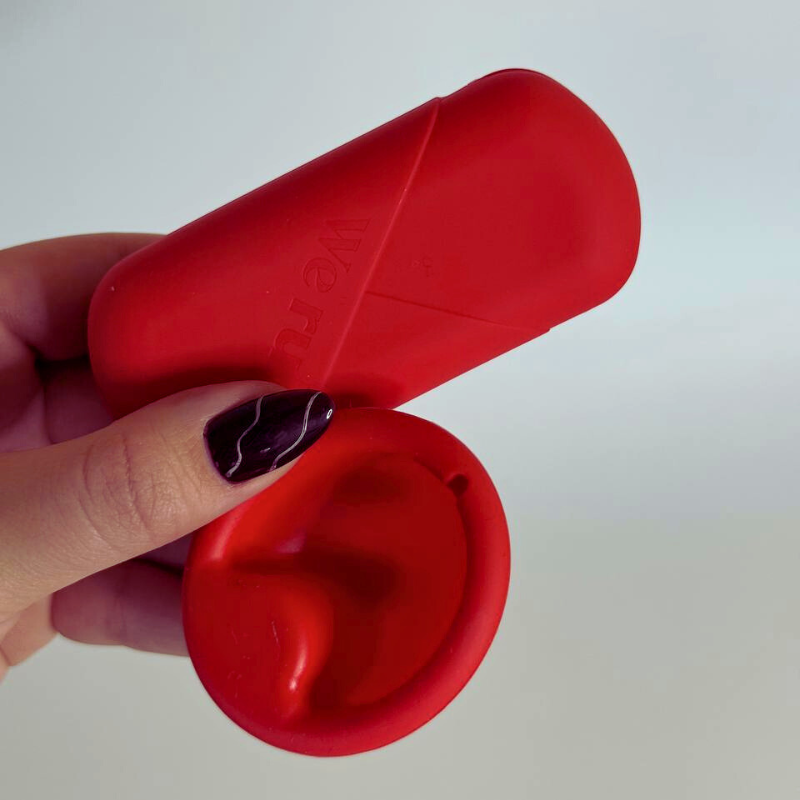 disco menstrual de we rule y su estuche sostenidos por una mano
